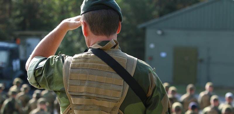Soldat i giv akt, med ryggen til kamera. Foto.