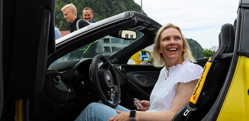 Sylvi Listhaug i en gul sportsbil. Smilende. Foto.