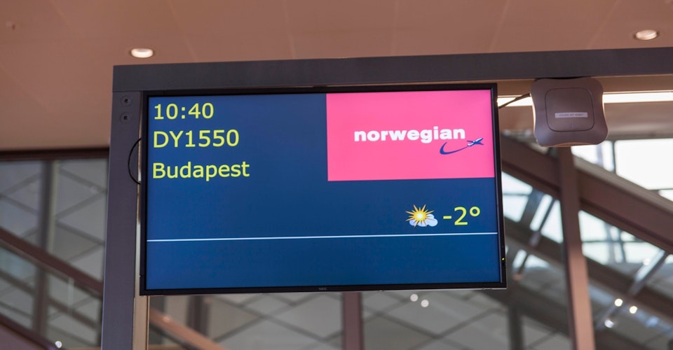 Skjerm ved gate på flyplass med Norwegian-logo
